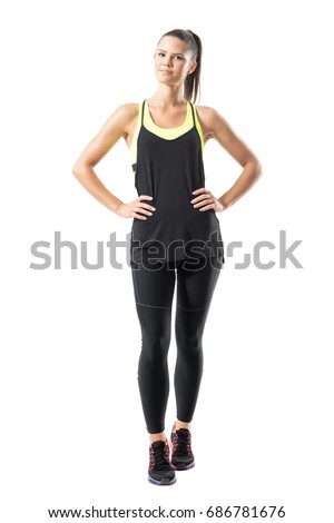 Satisfied confident active healthy woman in sports clothing with hands on hips. Full body length portrait isolated on white background.