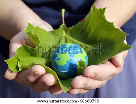 Environmental conservation Concept: Hands of an environmentally minded Person holding a leaf for protection of small eco friendly blue and green globe of the earth.