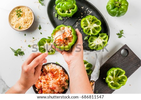 Autumn recipes. Home stuffed bell pepper with minced meat, carrots, tomatoes, herbs and cheese. Cooking process. On white marble table. Top view. Woman stuffing pepper. Female hands in picture.
