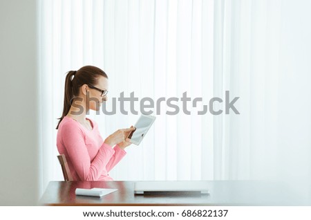 Young woman sitting at office desk using tablet. 