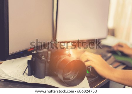 Photographer editing and retouch photos with camera, double screen at home 