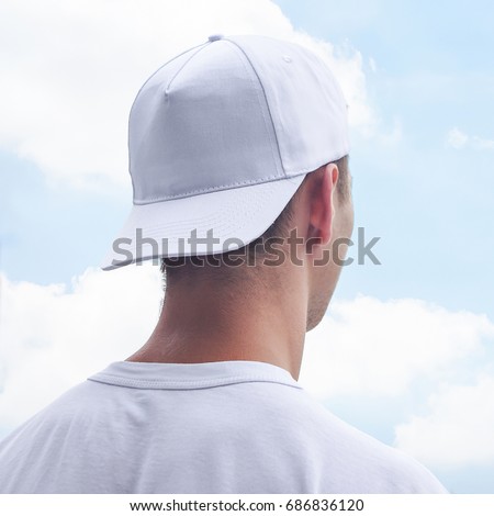 Young man in a white cap and t-shirt. White baseball cap mockup. Close-up Royalty-Free Stock Photo #686836120