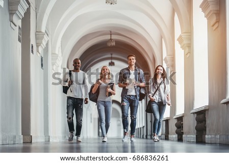 Multiracial students are walking in university hall during break. Royalty-Free Stock Photo #686836261