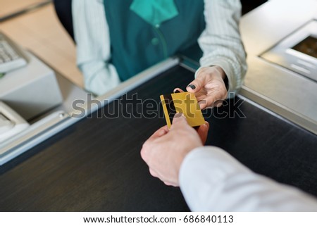 The hand of an unknown buyer gives gold card to the seller - cashier for payment in supermarket