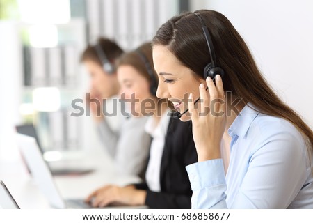 Happy telemarketer working at call center with other employees in the background Royalty-Free Stock Photo #686858677
