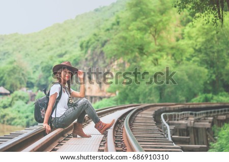 Beautiful Asian girl in casual wear with cowboy hat sitting on rail, adventure and outdoor concept 
