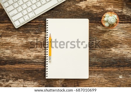 Flat lay wireless keyboard, cactus and blank notebook on old wooden desktop background