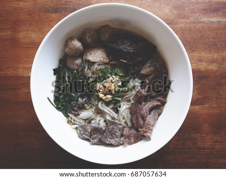 Top view picture of beef noodle on white plate above old wooden table.  soft tone color