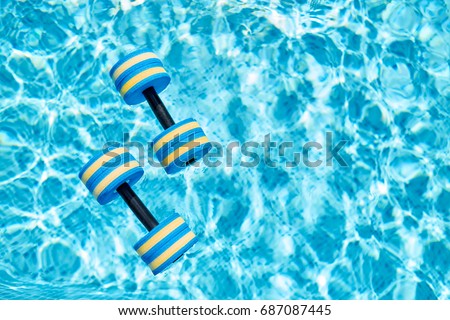 Top view - pair of dumbbells for aqua aerobics float on the surface of water in swimming pool on a warm summer day Royalty-Free Stock Photo #687087445