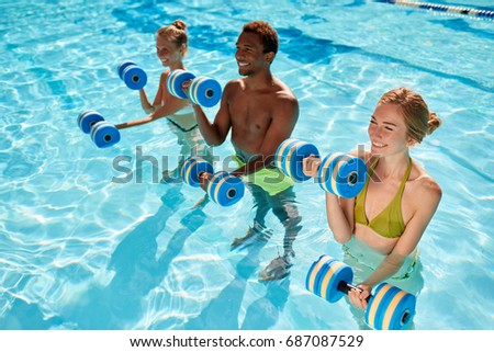Side view - three young people two caucasian girls and an African American man doing aqua aerobic with dumbbells in swimming pool on warm summer day Royalty-Free Stock Photo #687087529