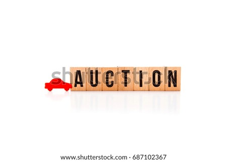 Car Auction - wooden block letters on white reflective background with red wooden car shape
