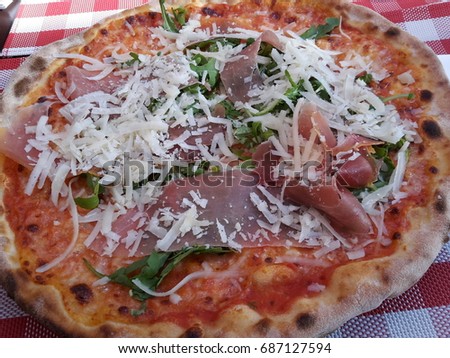 Freshly wood oven baked pizza with arugula and parma ham