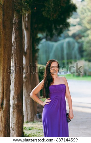 The girl in a long purple dress walking in the park