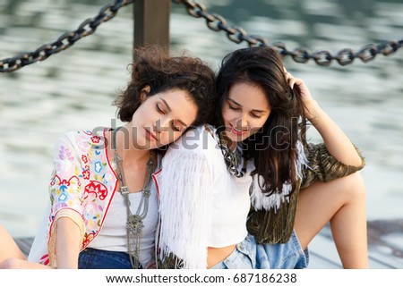 Two young happy fashion women painting a picture on an easel on a warm sunny day at nature. Art therapy, relax and hobby concept