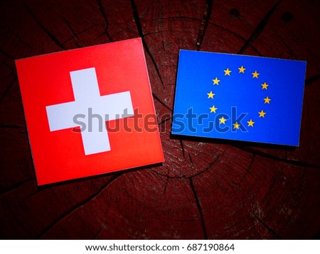 Swiss flag with EU flag on a tree stump isolated
