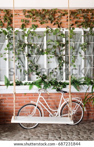 Retro vintage bicycle in front of the old brick wall and swing in the garden