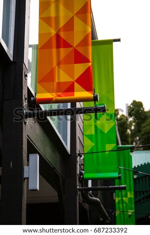 Tall green and orange flags with triangle patterns hung from a building.