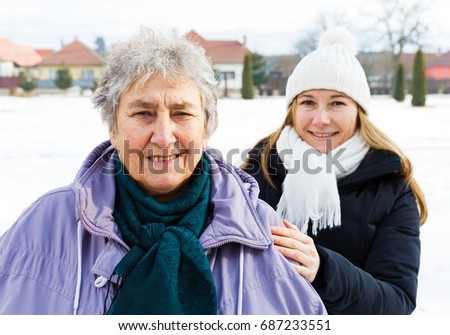Photo of happy elderly woman and young caregiver 