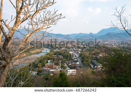 Wide angle picture From Mount Phousi, great view of the city of Luang Prabang in Laos. Many traditional  houses with trees and a river. Cloudy day.