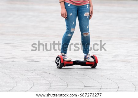 Young woman riding an electric board on the city square. New movement and transport technologies. Close up of dual wheel self balancing electric skateboard. People on electrical scooter outdoors