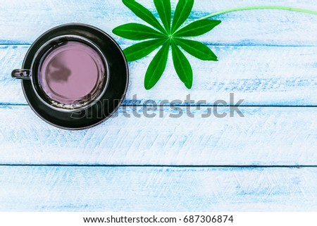 cup of coffee and green leaves flowers on wooden background. cover, card,  copy space.