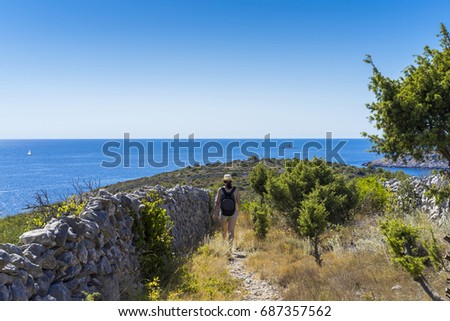 Woman walking in beautiful nature and landscape in Dalmatia Croatia. Lovely blue ocean and clear sky. Calm, peaceful and happy outdoors photo.