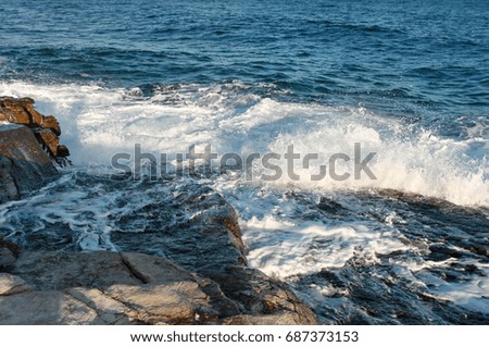 White sea foam splashing on sea stones. Rock stones against blue sea water. Island of Thassos, Greece