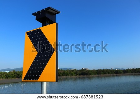 Solar cells for electricity production, electricity for traffic signals. Road traffic signs on side way. The arrow traffic signs and blue sky.
