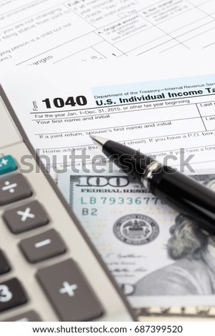 Tax form with calculator, pen, and dollar banknote