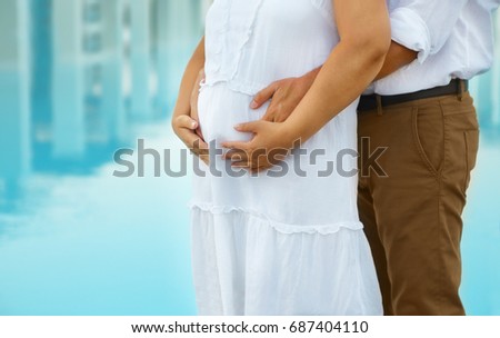 Man and young pregnant woman hugging outdoors. Family and childbirth concept