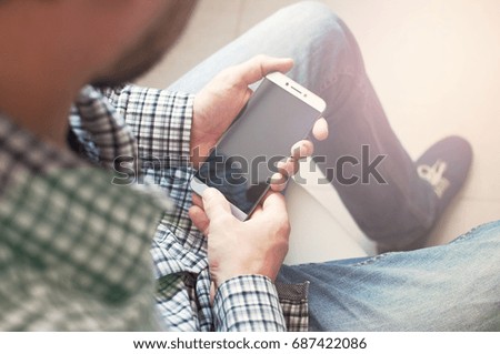 Top view of the hand of a young man in a checkered shirt using a smartphone. Touch screen phone business.