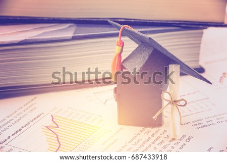 Black graduation cap / hat, a diploma or certificate and a small book on sheets / documents. Concept of international graduate study program, students seek to study at the best and famous institution.