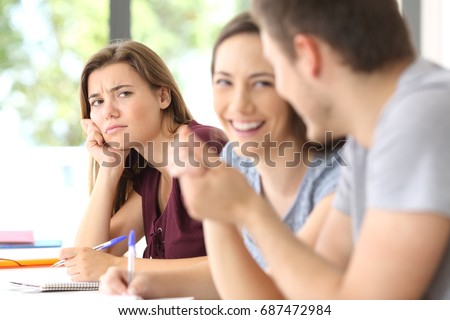 Couple in love and a jealous classmate watching them in a classroom Royalty-Free Stock Photo #687472984