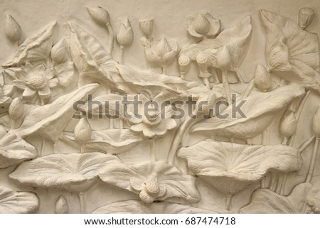 Beautiful white lotus stucco patterned on the boundary wall. Vintage white wall bas-relief stucco in plaster, depicts Lotus flowers background. Royalty-Free Stock Photo #687474718