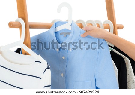 Woman hand picking women's fashion clothing hangs on a wooden clothes rack in a clothes store. Fashion and Accessory Concept. Isolated on white background