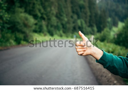 Hand of hiker woman at rural mountain road. Mountains road