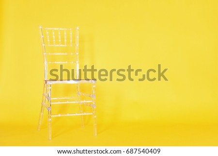 Transparent plastic chair on a yellow background in a photo studio