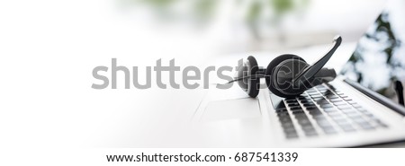 Communication support, call center and customer service help desk. VOIP headset on laptop computer keyboard. Royalty-Free Stock Photo #687541339