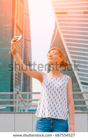 Young girl taking selfie photo on skyscrapers background