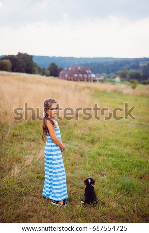 Girl stands with a puppy on the field