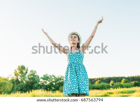 Beautiful teenage girl in blue dress dance to camera on the summer field, Sun Light. freedom concept