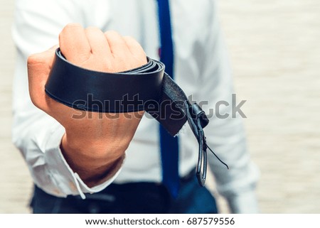 Male businessman hold trouser belt in hand with angry sign. Can be used for violence scenes, dangerous people, make scare someone
