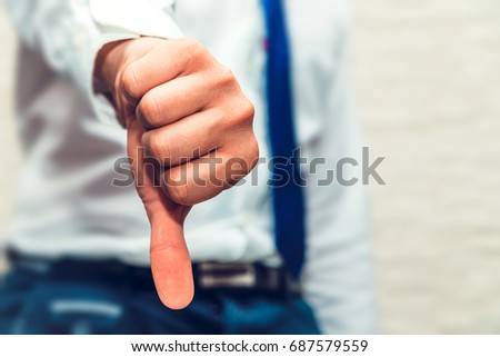 Male hand show thumb down. Businessman with white shirt and blue tie. Something got wrong, is not accepted, do not like, not well, loser or someone lose out Royalty-Free Stock Photo #687579559