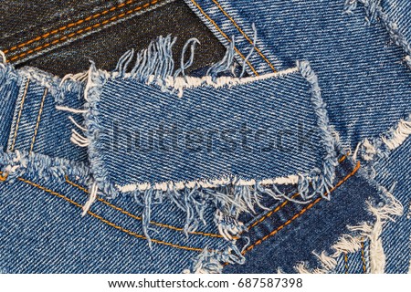 denim blue patch on ripped destroyed denim  torn blue scraps. Denim double seam jeans fashion background