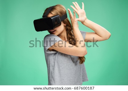 Young beautiful woman on a green background with virtual reality glasses.