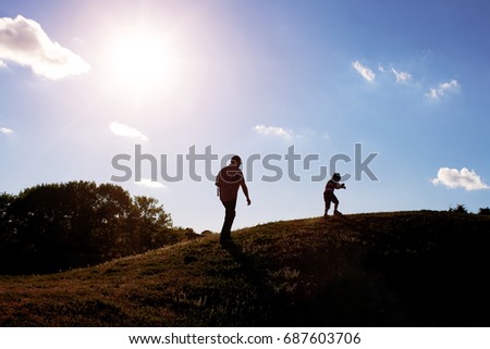 Silhouette, happy family with children playing on meadow, sunset, summertime         