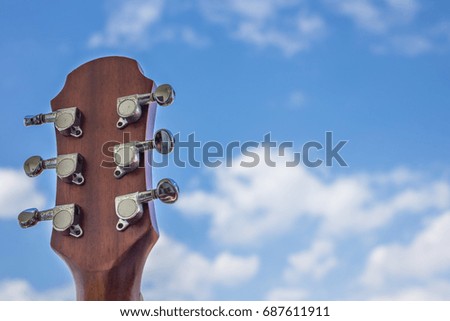 Guitar head on sky background and clouds