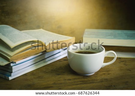 Cup of hot coffee and stack book on wooden table in the morning. Relaxing time with coffee. Reading concept