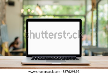 Laptop with blank screen on wood table and coffee shop background. Clipping path include. Royalty-Free Stock Photo #687629893