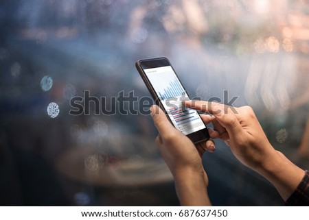 Close up male hands holding smartphone with graph chart in night
